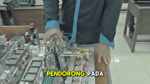 Rangkaian panel otomasi PLC dan mekanisme aktuator yang sedang diuji di meja praktik.